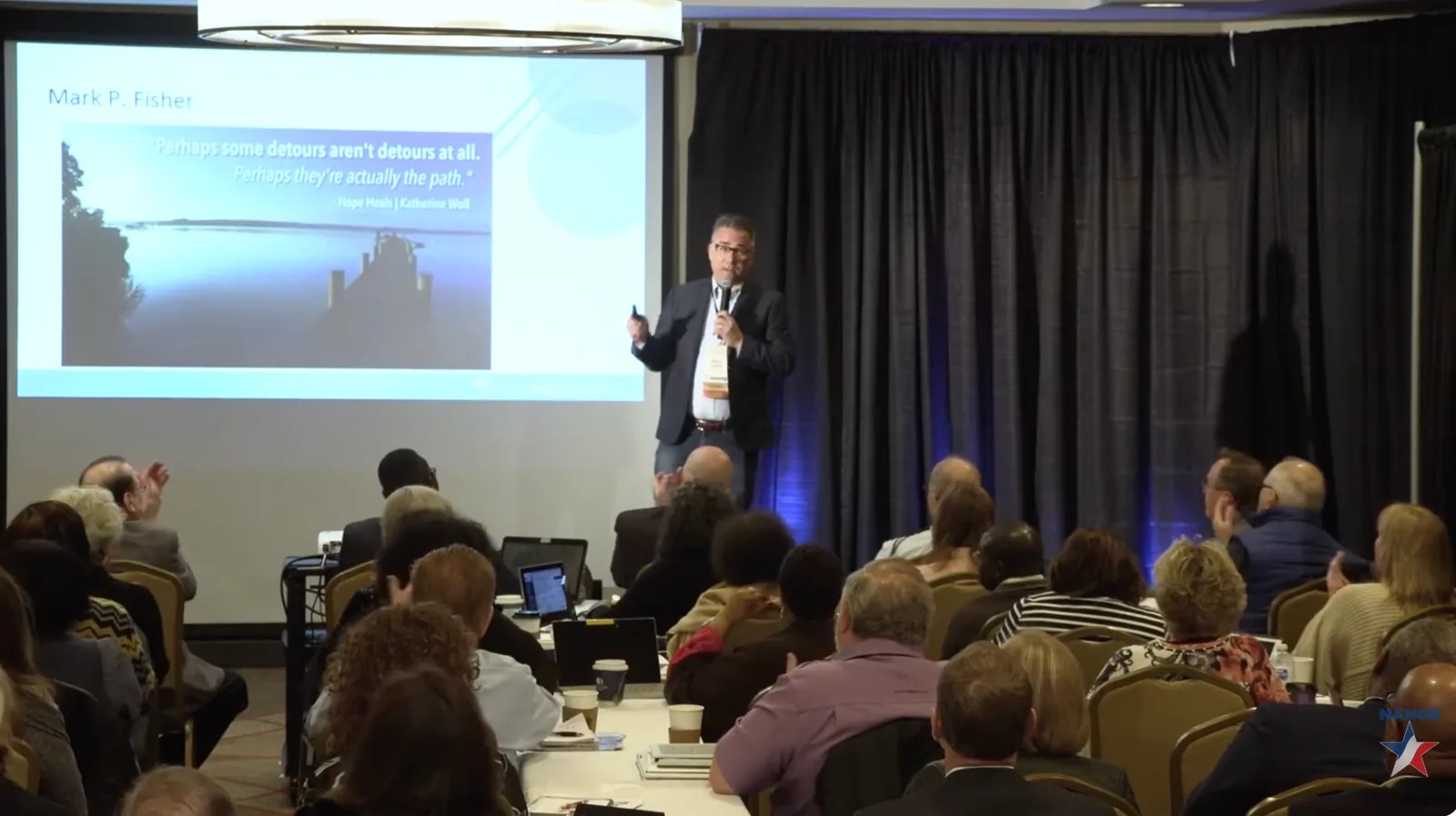 Mark P. Fisher speaking to a large group from the front of the room